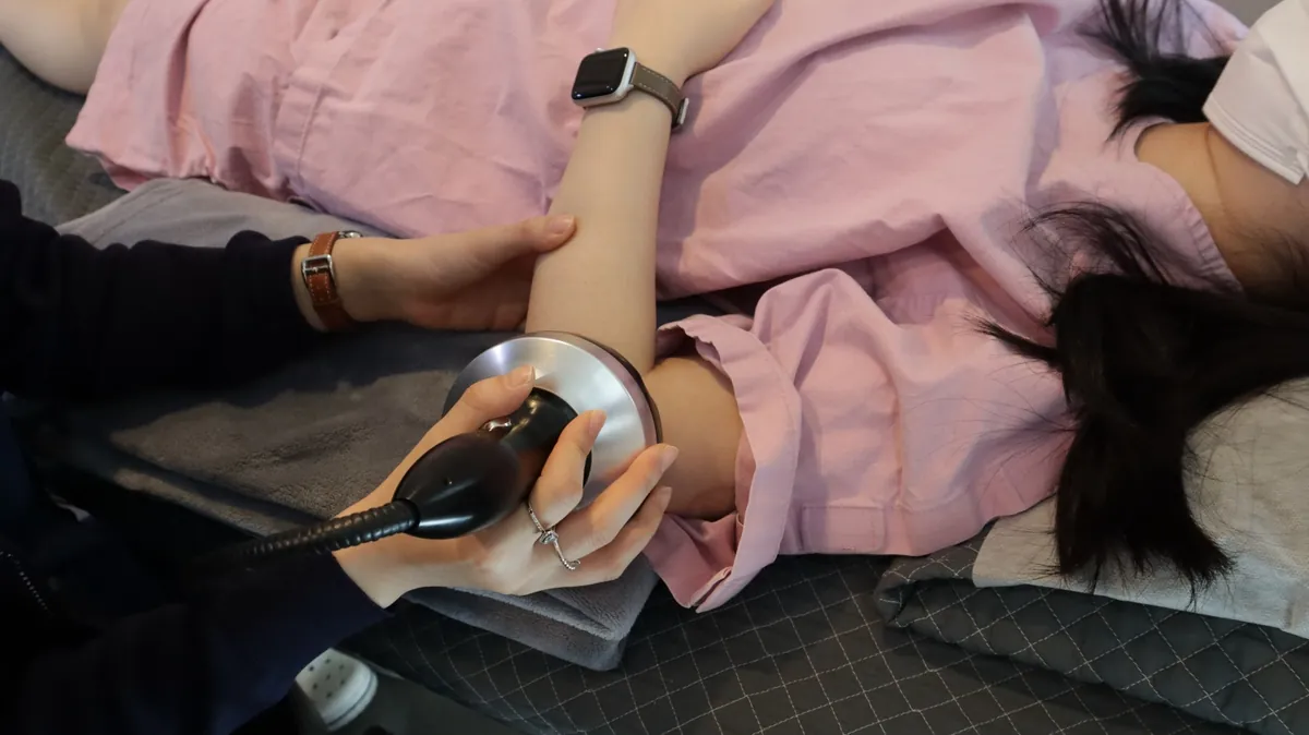 팔꿈치에 체외충격파 치료를 받고 있는 환자